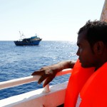 A migrant on the MOAS ship MV Phoenix looks at the wooden boat from which he was rescued 10.5 miles (16 kilometres) off the coast of Libya
